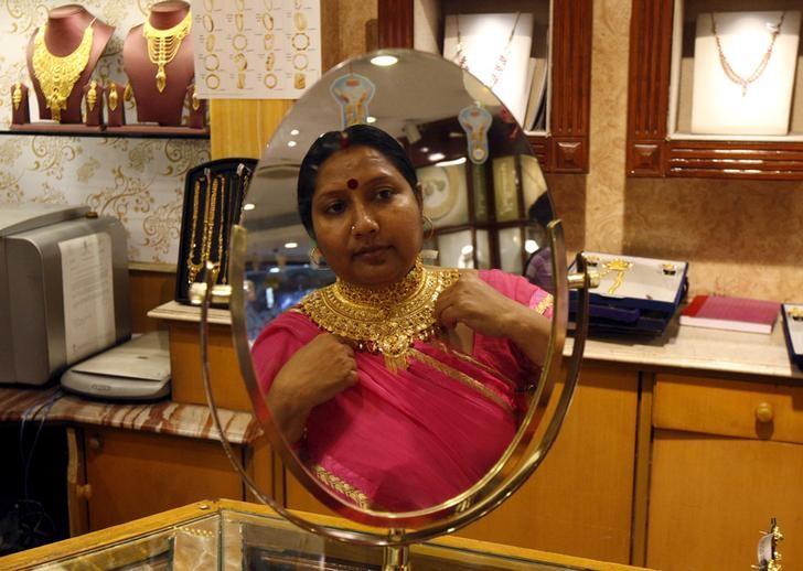 A woman is reflected in a mirror as she tries on a necklace at a jewellery showroom in Kolkata